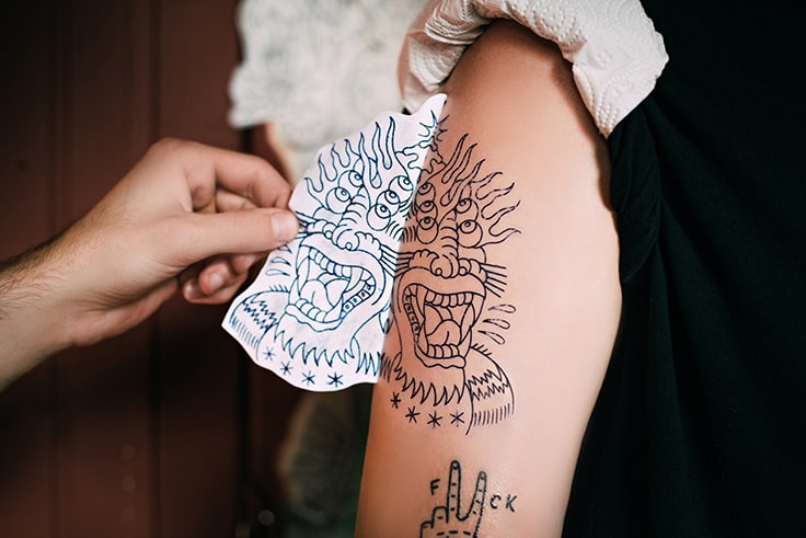 cropped shot of tattoo artist transferring tattoo