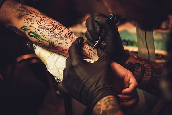 tattoo artist makes a tattoo on a mans hand